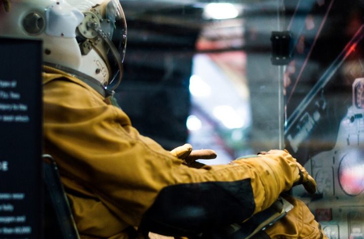 a person sitting in a chair wearing a gold astronaut suit
