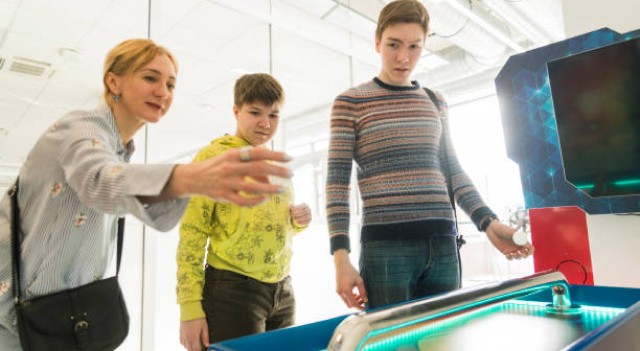 Two students and their teacher in the museum laboratory experimenting light energy. 