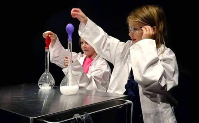  Two children in a laboratory doing a yeast, sugar and ballon Experiment.